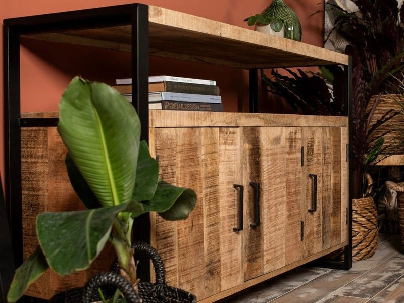 Buffet Vivana en manguier et métal noir près de plantes, devant un mur terracotta