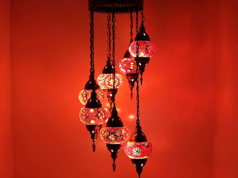 Lustre en mosaïque allumé, globes colorés projetant des motifs sur un mur rouge