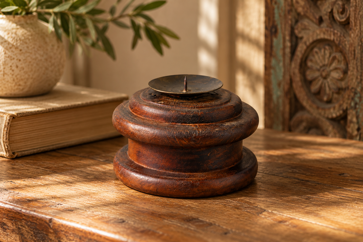 Small turned dark wood candle holder on a table, next to books